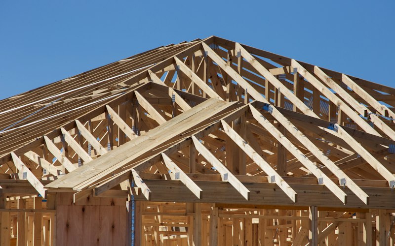 Roof trusses and eave framing on a small wood-framed building under construction, the stage when ADU gutter and downspout locations are set