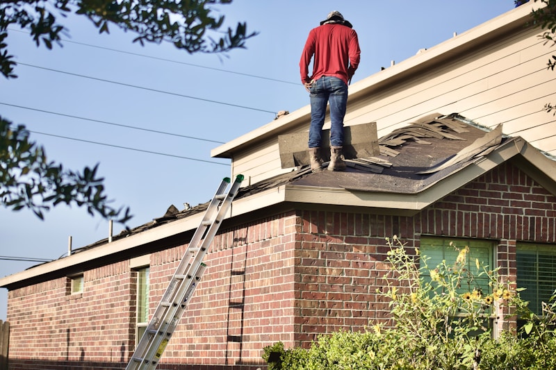 Construction worker standing on a residential rooftop during a building project with clear skies in the background
