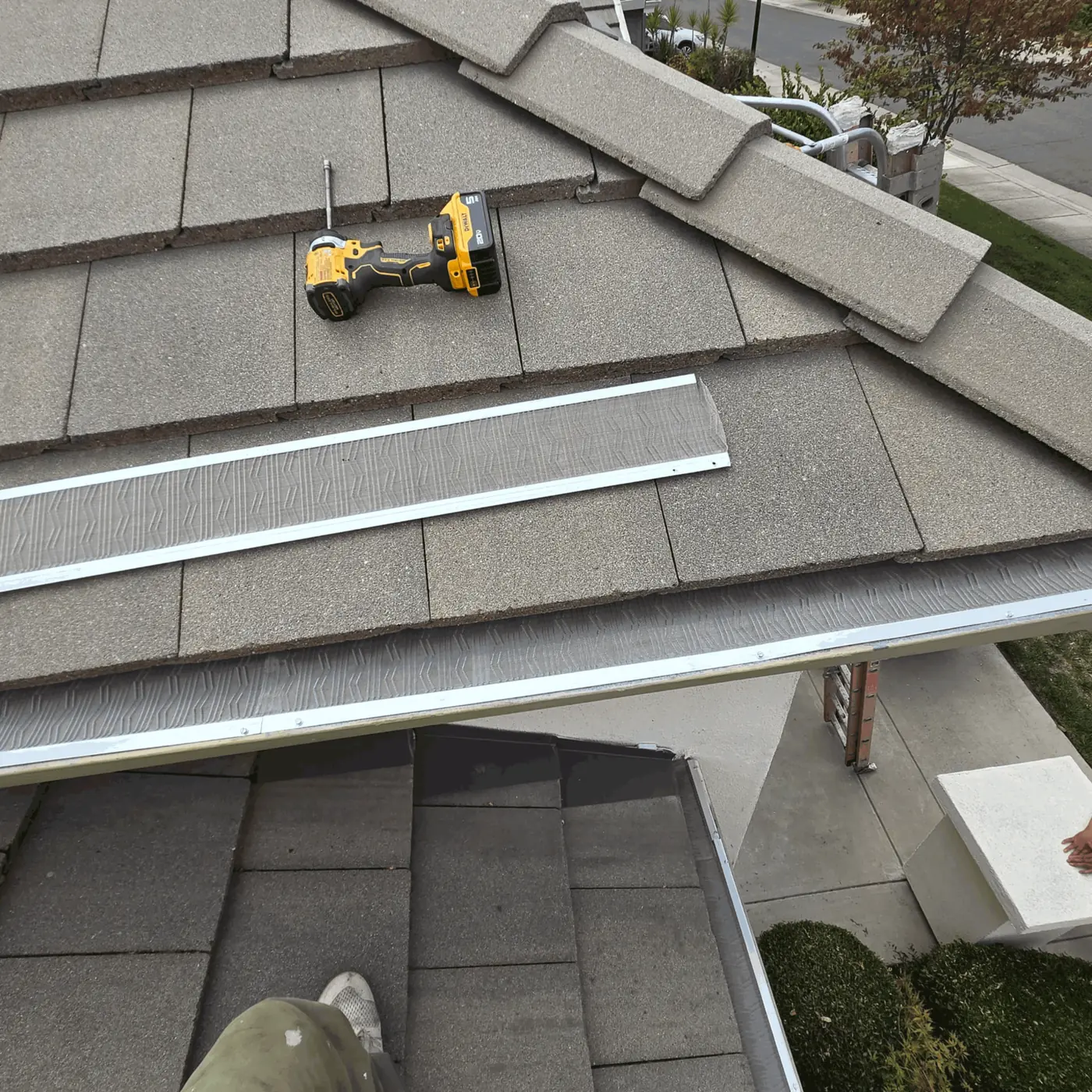 Micro-mesh gutter guard panels laid out on a flat concrete tile roof during installation