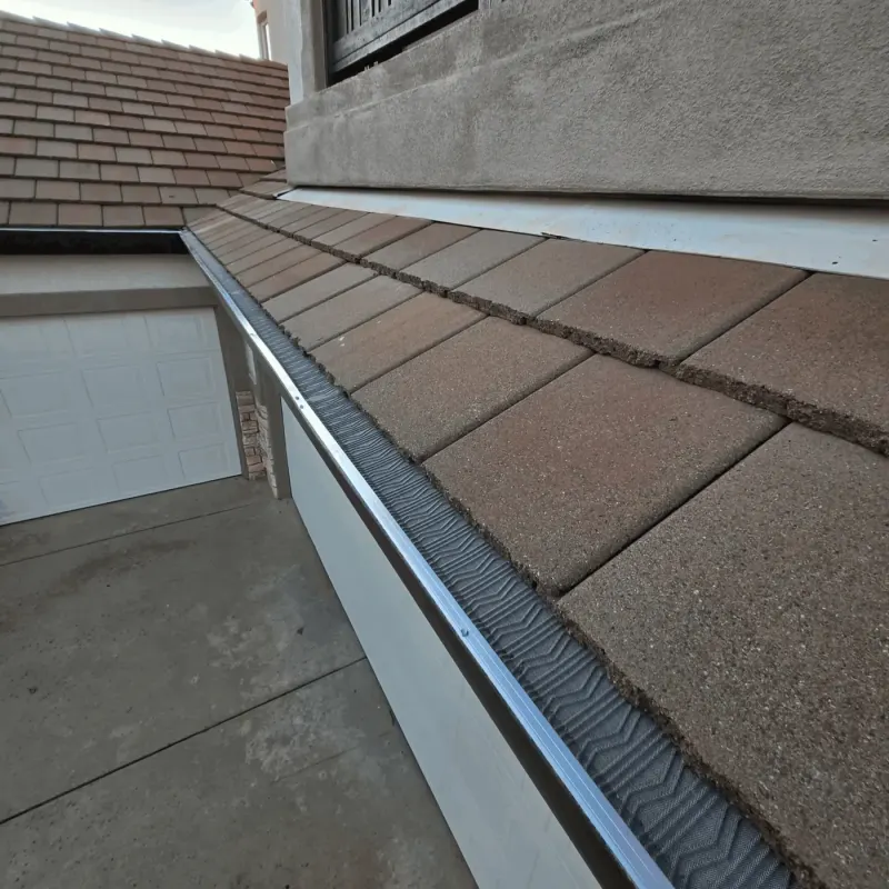 Micro-mesh gutter guard along a concrete tile roof over a two-car garage on a stucco home